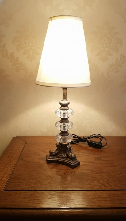 Arlumina Cherub’s Grace Antique lamp, etched-gold pillar base with a white pleated shade and silk tassel detail.